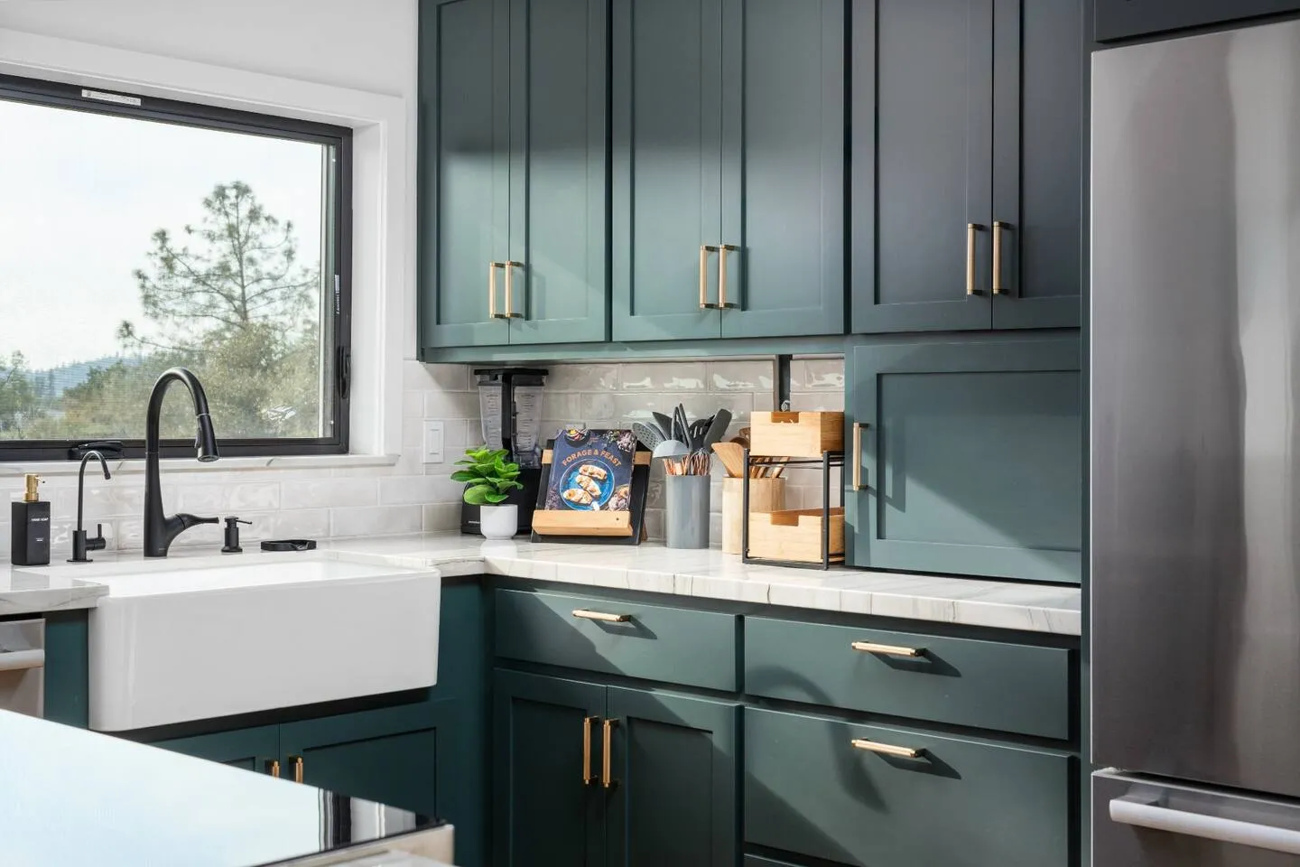Pine-green kitchen with farmhouse sink and brass hardware
