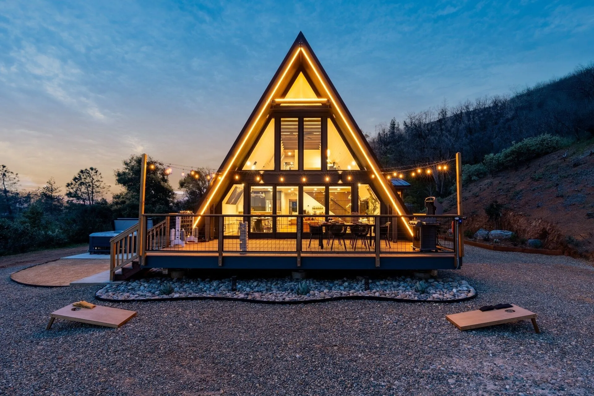The A-frame glowing warmly at dusk under a deep blue sky